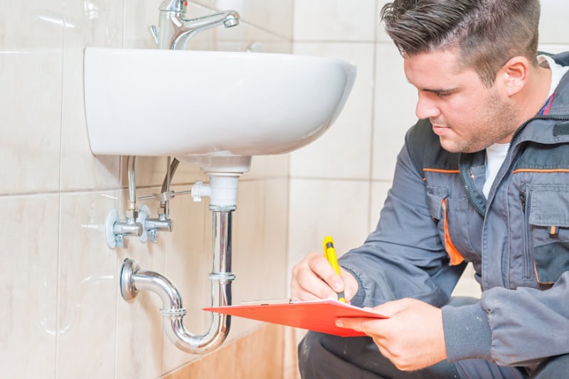 Plumber inspecting a sink in a bathroom