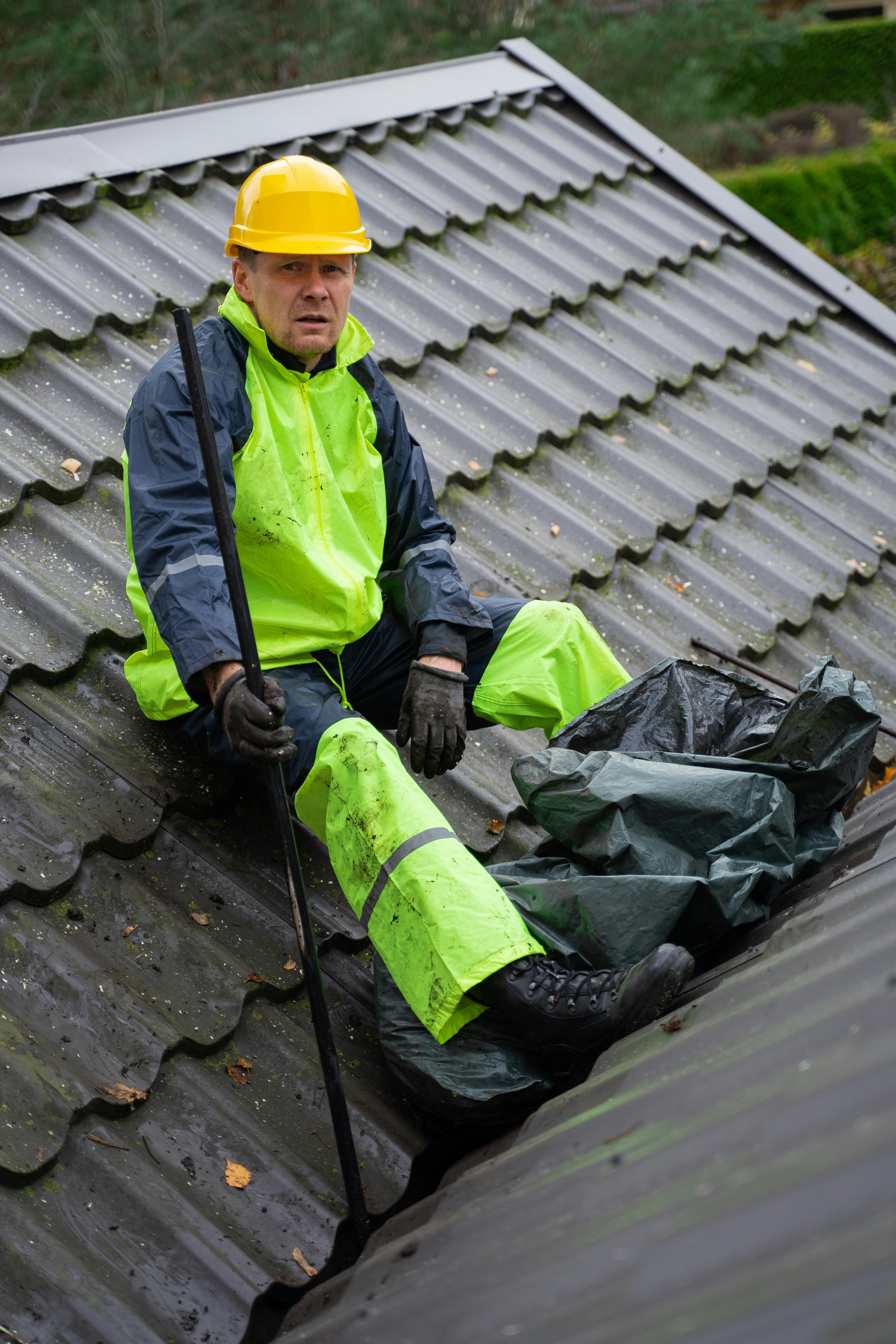 Person in safety gear on a roof with a black bag